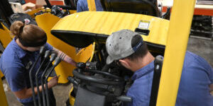Close-up of two technicians performing hands-on maintenance on a Hyster forklift.