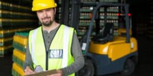 Portrait of smiling male worker writing on clipboard in warehouse